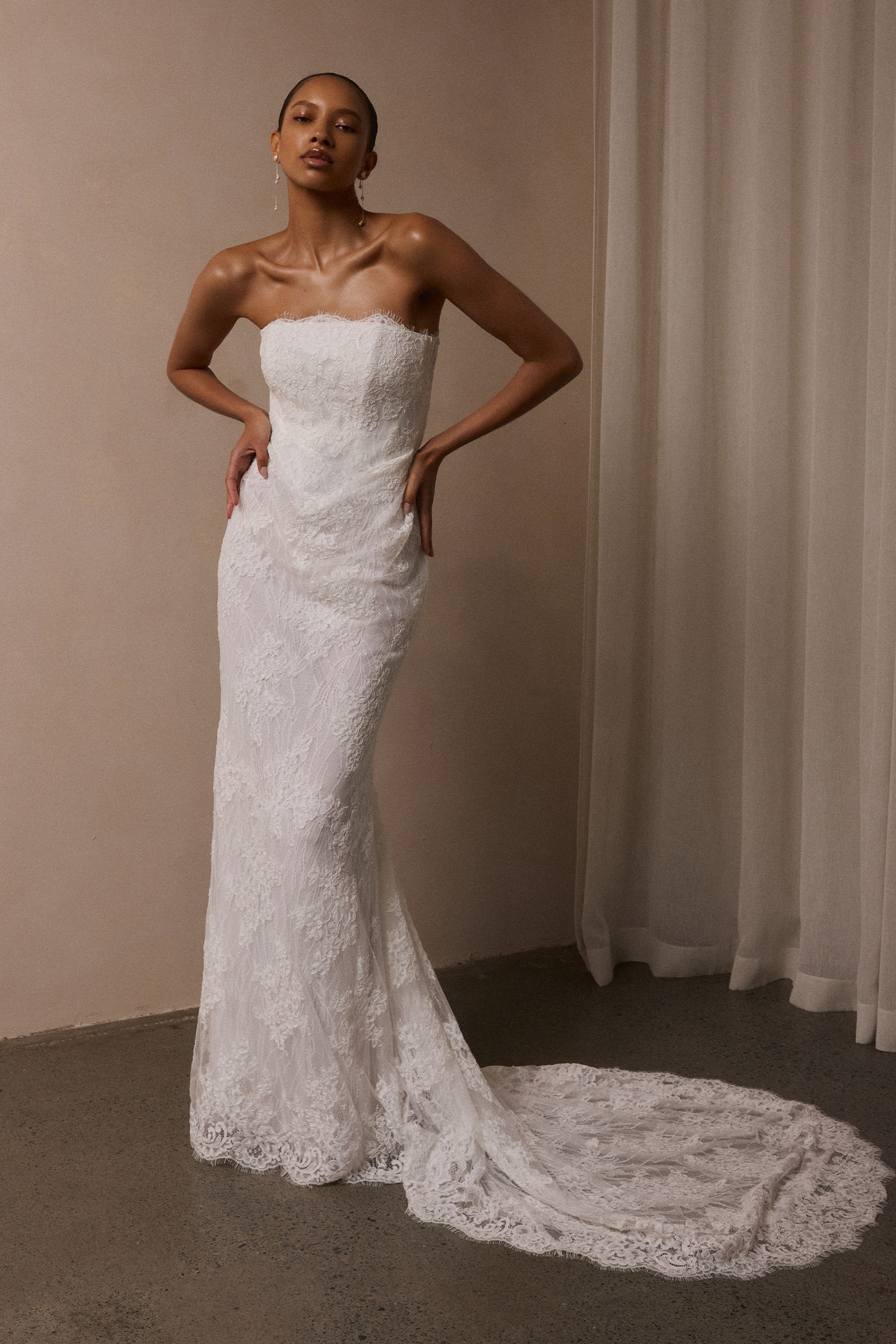 A woman wearing a strapless white lace wedding gown with a long train_XS_
