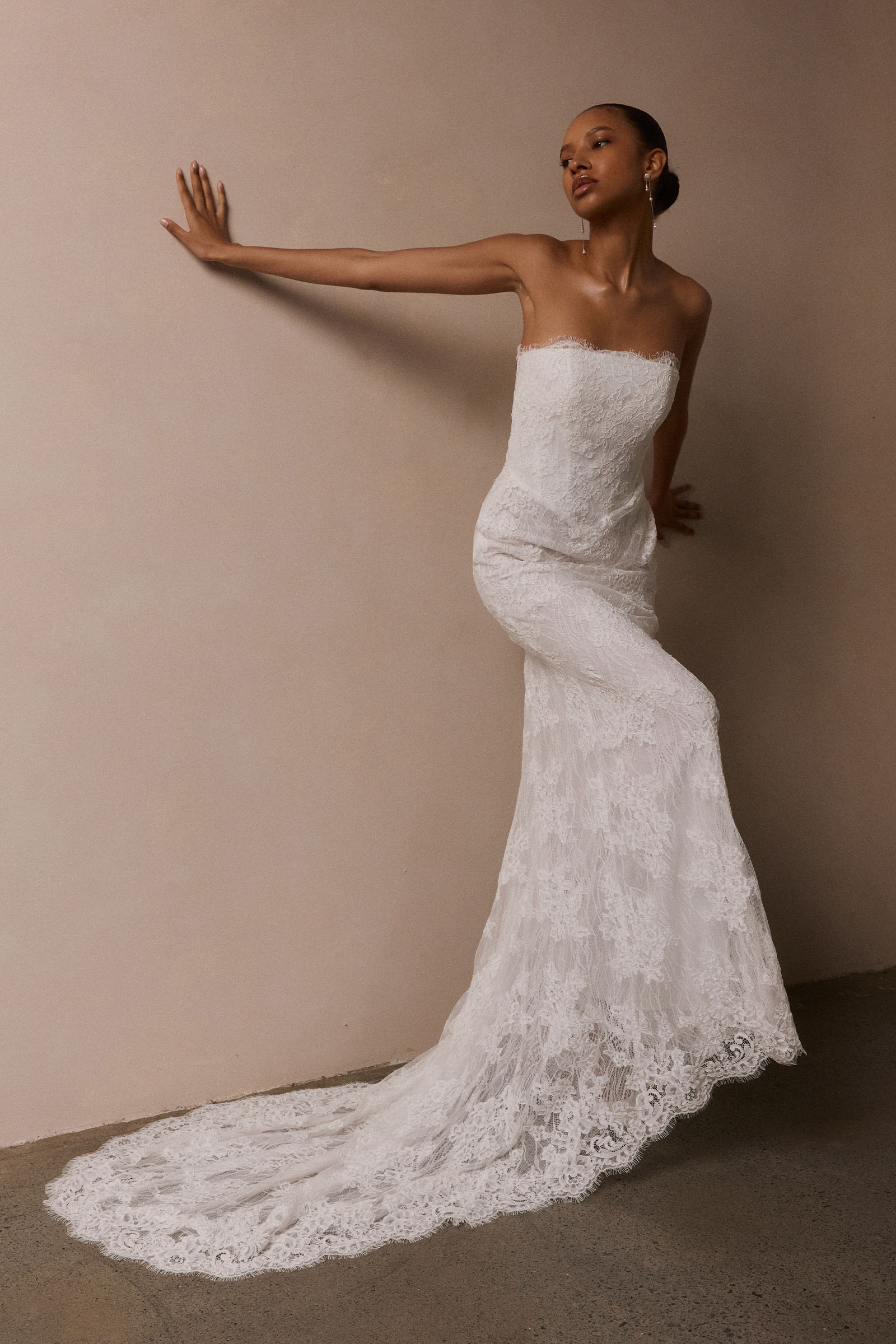 A woman wearing a strapless white lace wedding gown with a long train_XS_