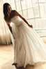 A woman wearing a strapless white wedding gown with a fitted bodice and flowing tulle skirt