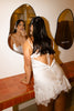 Woman in a satin bridal slip dress getting ready in a mirror