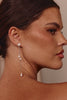 Close-up of a woman wearing pearl drop earrings with a neutral background