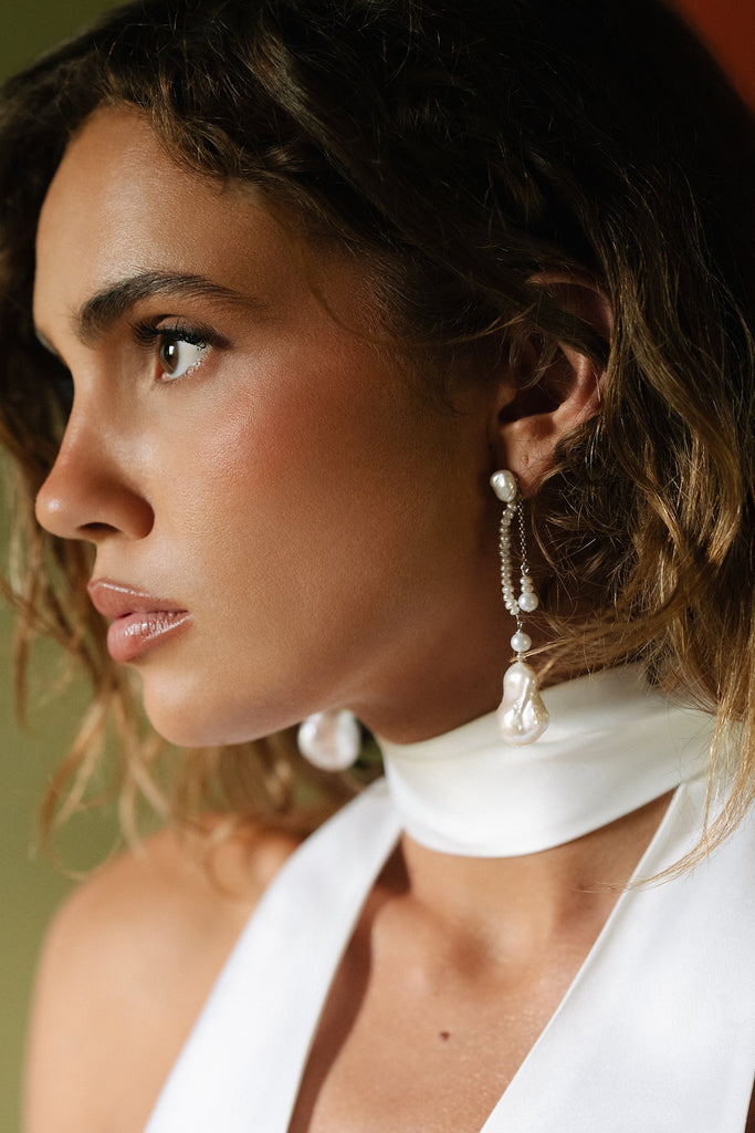Woman wearing pearl earrings with a blurred background
