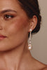 Close-up of a woman wearing pearl earrings with a neutral background