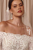 Bride wearing a lace wedding dress with a floral veil and pearl earrings