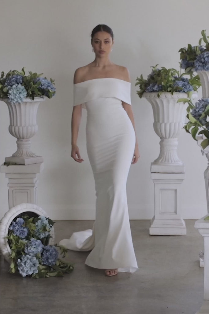 A woman walking in a strapless crepe wedding dress.